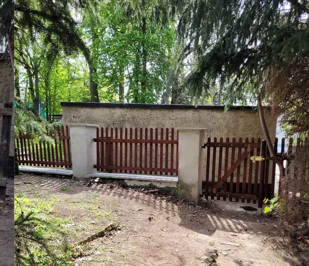 Nachher: neuer Holzzaun mit Tor zwischen verputzten Pfeilern, Mauer ausgebessert